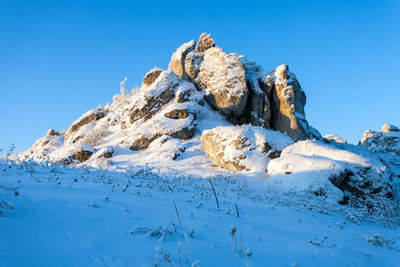 Low angle view of snowcapped mountain against clear blue sky