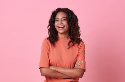 Portrait of smiling young woman against pink background