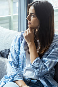 Young woman sitting on sofa at home