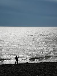 Silhouette man standing on beach against sky