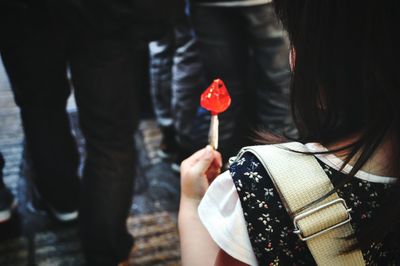 Rear view of girl with lollipop standing on road