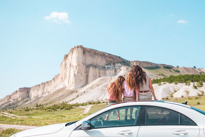 Rear view of woman on car against sky