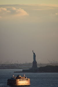 Statue in sea against cloudy sky