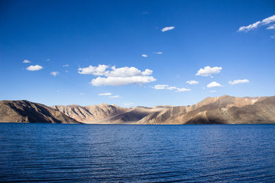 Pangong lake blue waters with mountain and clear blue sky nad clouds in ladakh india