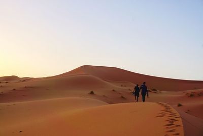 People walking on desert against sky