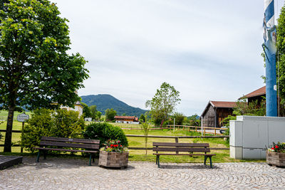 Park bench by building against sky