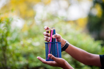 Close-up of woman holding hands against blurred background