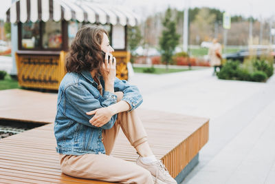 Side view of woman sitting outdoors