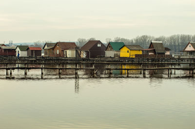 Houses by lake and buildings against sky