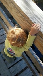 High angle view of boy climbing on railing at footbridge