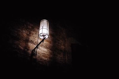 Low angle view of illuminated lamp on wall