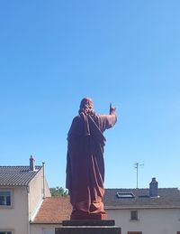 Low angle view of person standing against building against clear blue sky