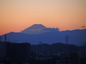 Silhouette cityscape against sky at sunset