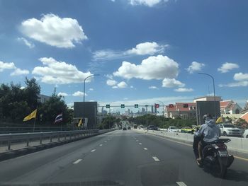 Cars on road against sky in city