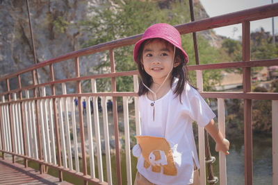 Portrait of smiling girl standing against railing