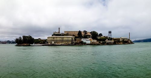 Buildings by sea against sky