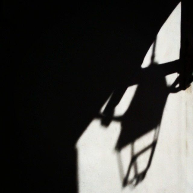 indoors, shadow, bicycle, silhouette, copy space, part of, wall - building feature, close-up, one person, sunlight, cropped, wall, high angle view, dark, table, person, home interior, built structure, transportation