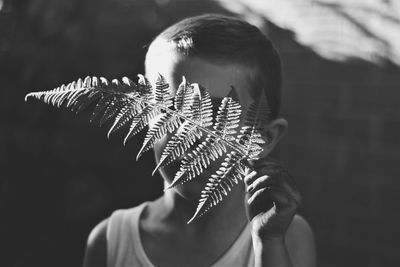 Boy holding fern while playing outdoors