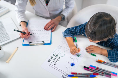 Teacher and student drawing on table in classroom