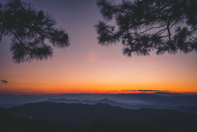 Scenic view of silhouette mountains against orange sky