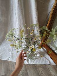 Midsection of woman holding bouquet at home