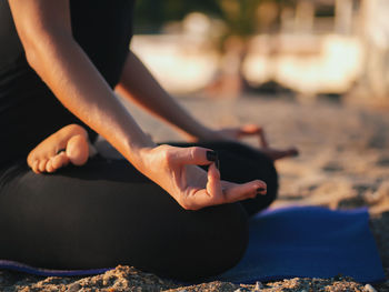 Low section of woman doing yoga at beach