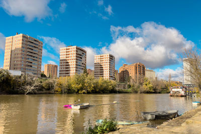 Buildings by river against sky