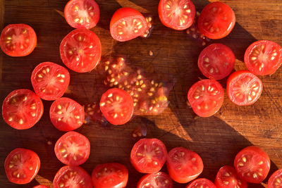 Above view of grape tomatoes cut into halves on wood cutting board