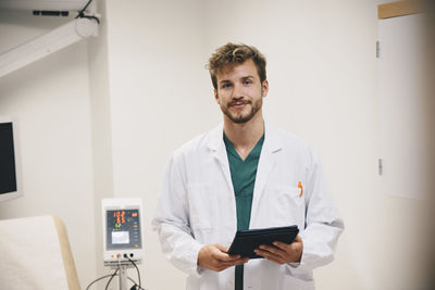 Portrait of confident male doctor standing with digital tablet at hospital