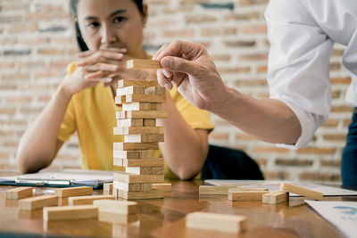 Woman looking at man stacking toy blocks at table