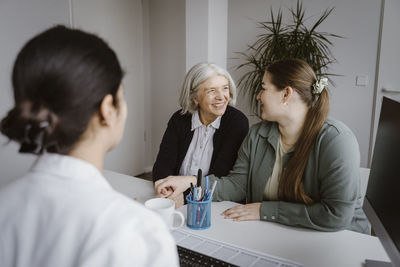 Daughter talking to mother during consultation with doctor in clinic