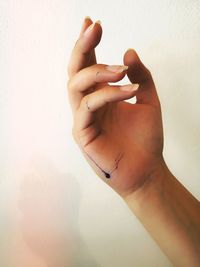 Close-up of woman ink on hand against wall