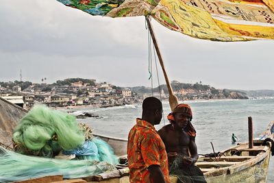 People standing by sea against sky