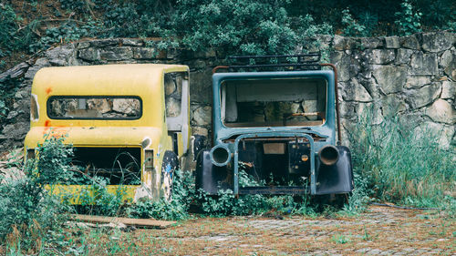 Discarded old cars left for years by the wall. cars next to each other in overgrown grass.