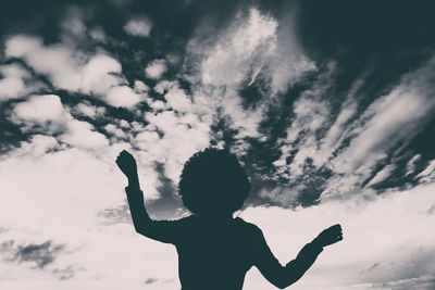 Rear view of silhouette boy standing against sky