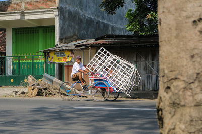 Man riding tricycle against houses