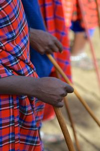 Midsection of people holding stick