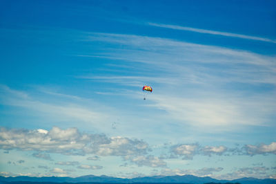 Low angle view of person paragliding against blue sky