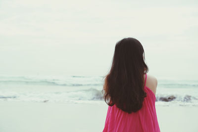 Side view of woman standing at beach against sky