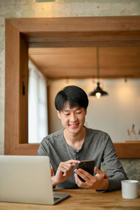 Young woman using mobile phone while sitting at home