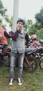 Portrait of friends standing on motorcycle