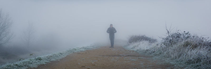 Person standing on footpath during foggy weather