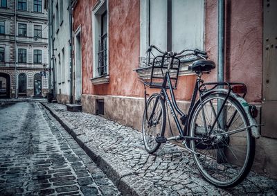 Bicycle parked on footpath against building