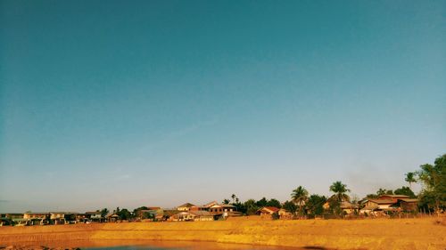 Houses on field against clear blue sky