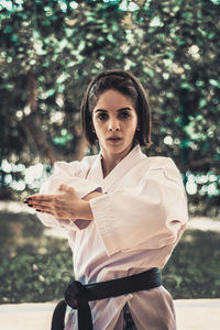 Portrait of young woman standing against trees