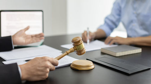 Midsection of lawyer holding gavel on table