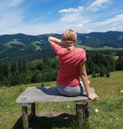 Rear view of woman sitting on seat against mountain