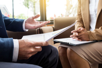 Midsection of businessman discussing with colleague while sitting on sofa