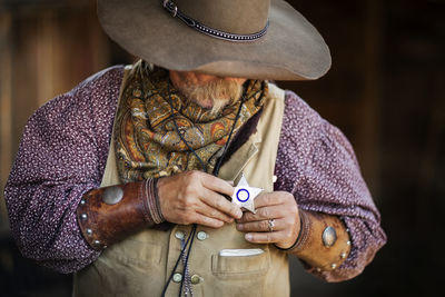 Senior male cowboy wearing star shaped badge at stable