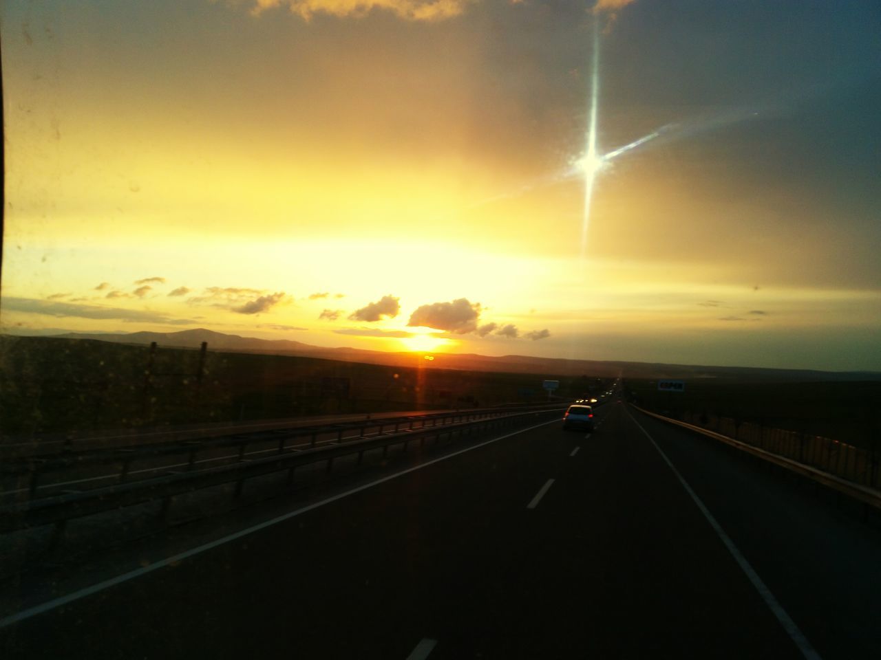 transportation, sunset, the way forward, road, sky, road marking, diminishing perspective, vanishing point, mode of transport, sun, cloud - sky, car, land vehicle, silhouette, orange color, travel, sunlight, on the move, nature, highway